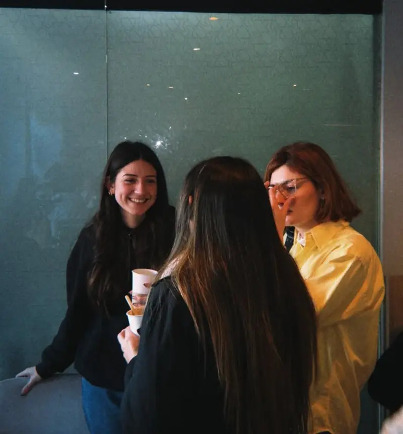 Tres personas conversando con café en la mano