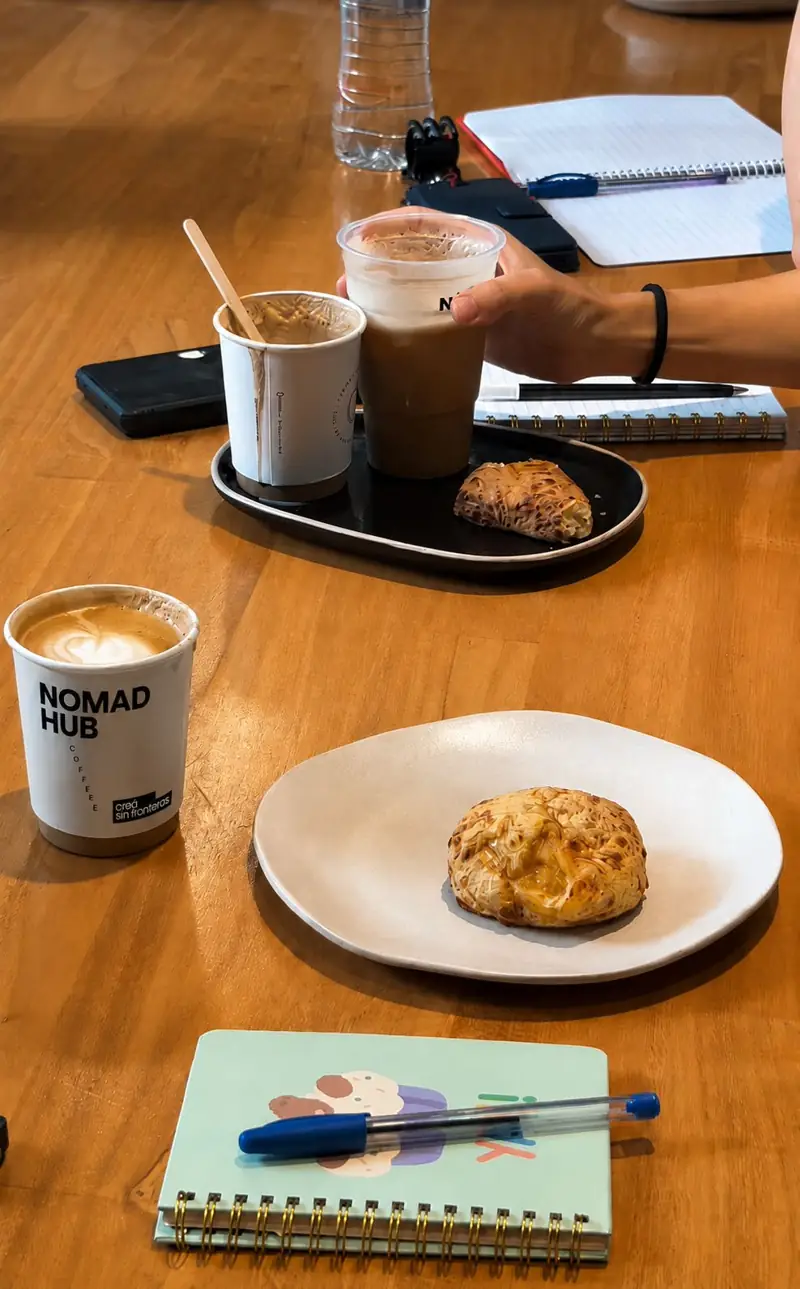 Café con latte art en un vaso Nomad Hub sobre una mesa de madera